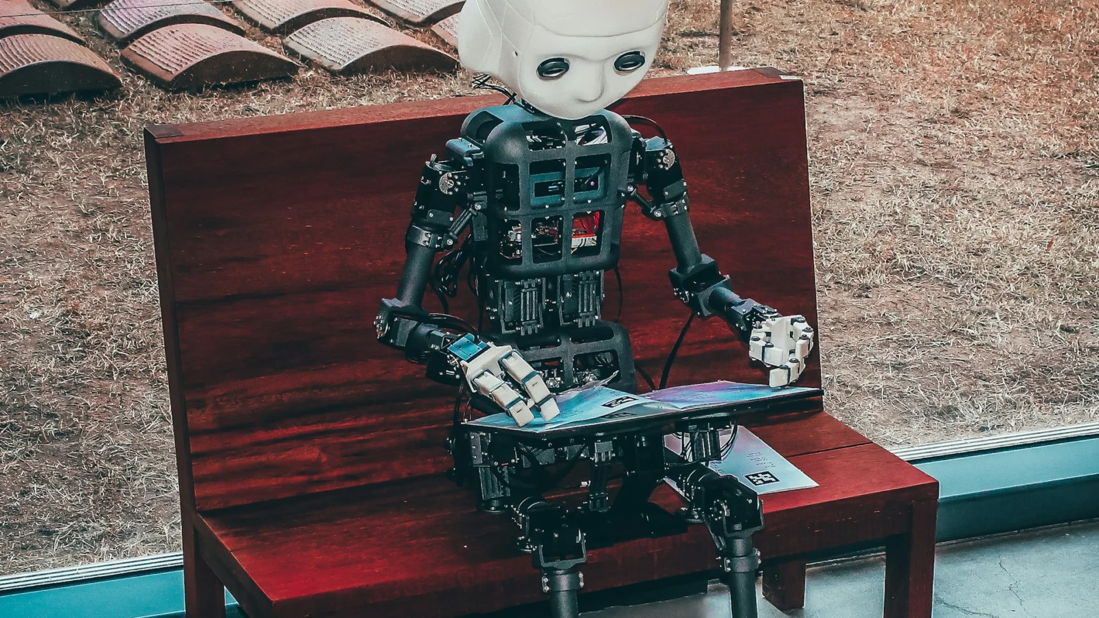 Small humanoid robot sitting on a park bench