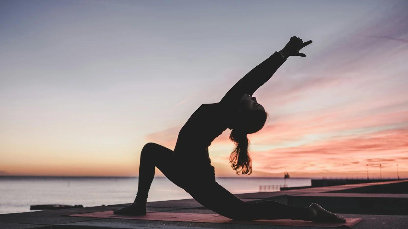 Person in a yoga pose silhouetted against a sunset