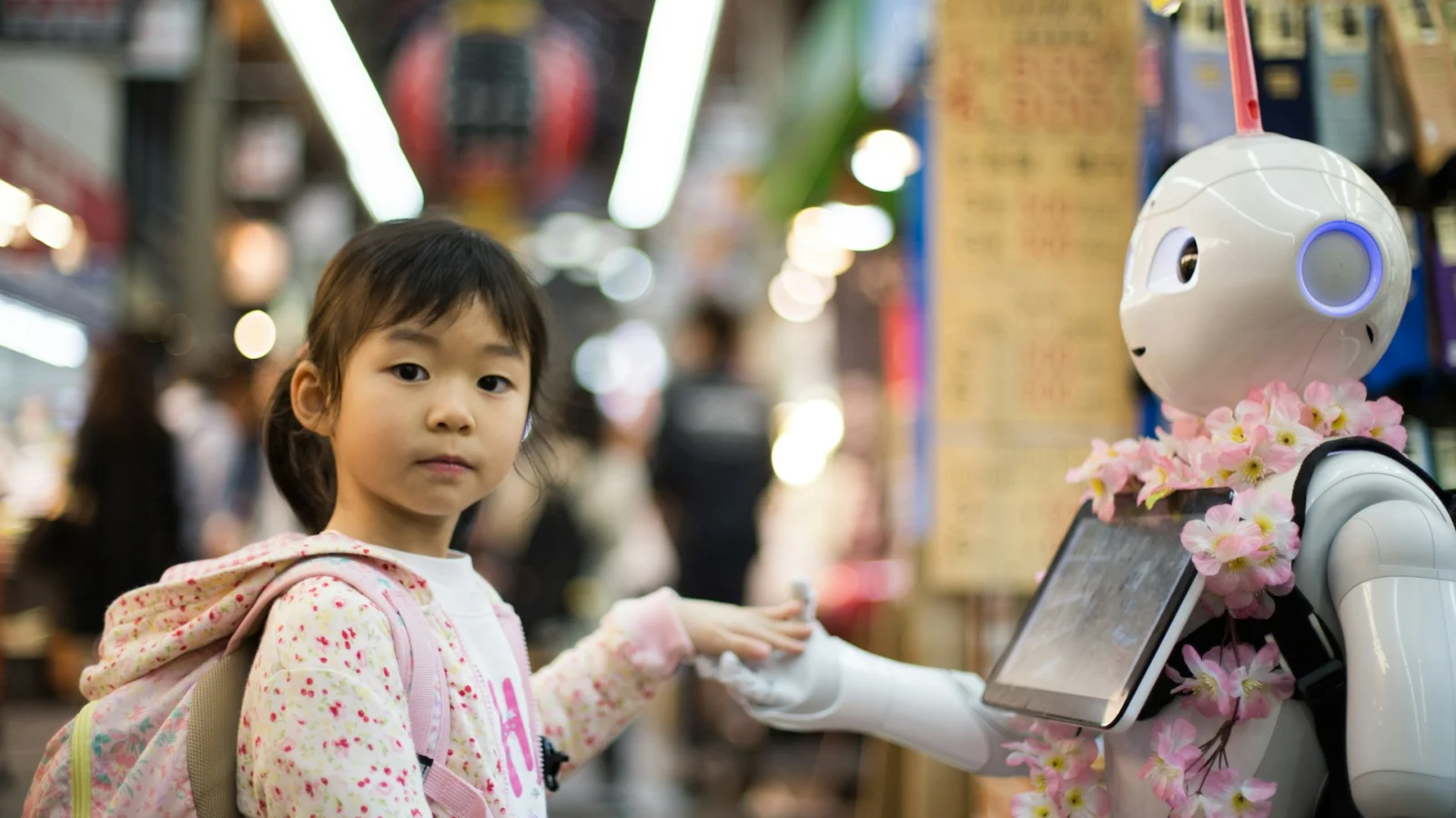 Child looking up at a friendly service robot in a shopping centre