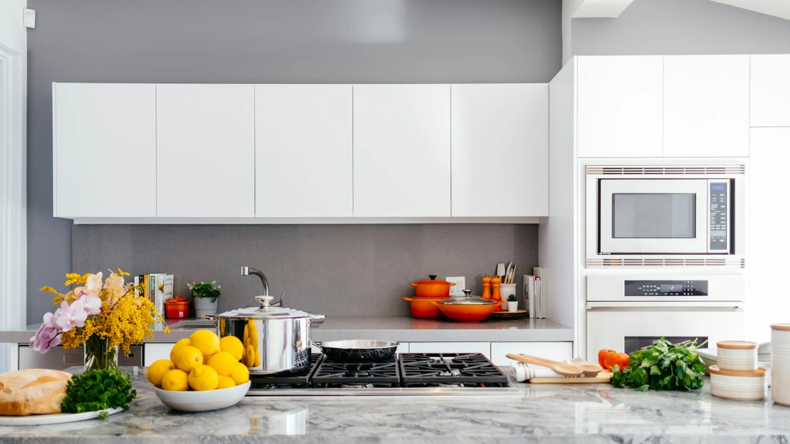 Modern white kitchen with a long worktop and fresh vegetables