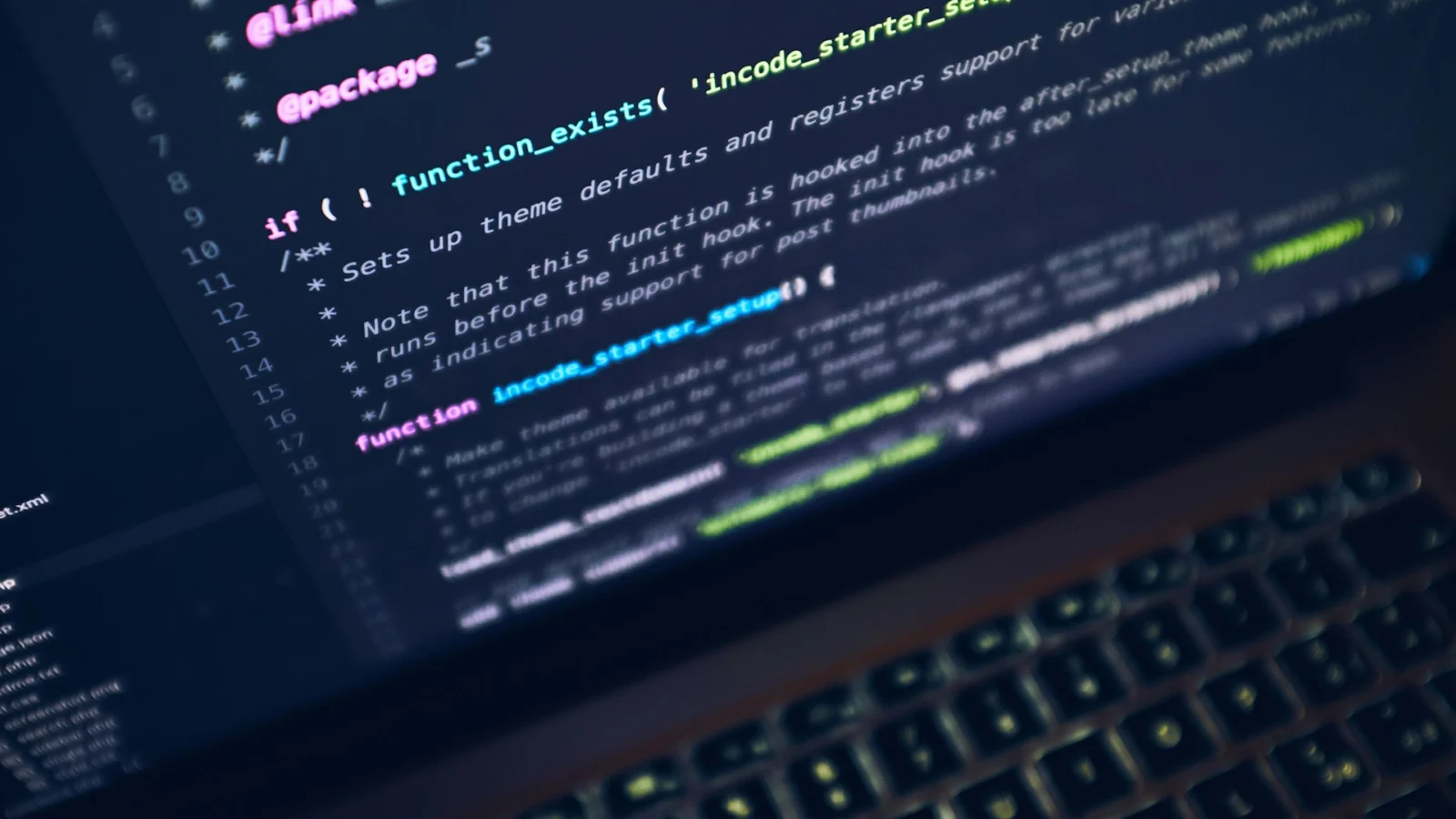 Laptop on a desk showing lines of code in a dark editor
