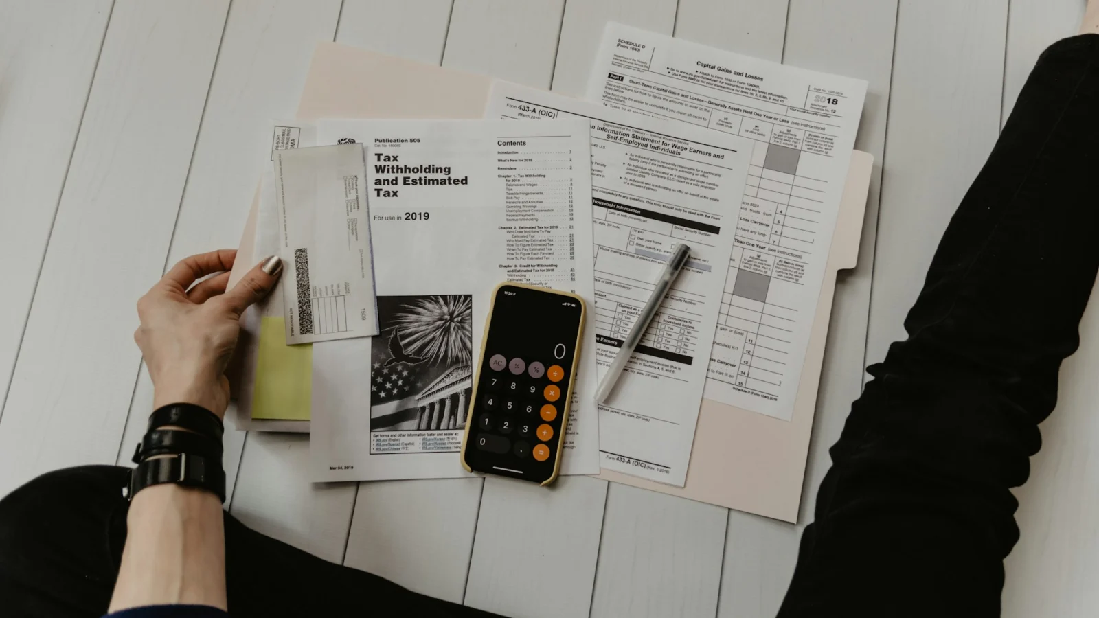 Person reviewing tax forms with a calculator
